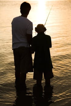 Silhouette of a father and his son fishing
