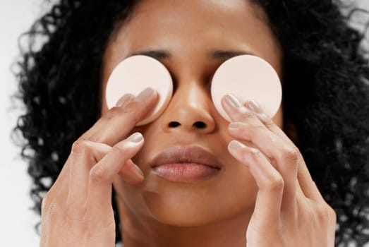 Close-up of a young woman holding powder puffs over her eyes