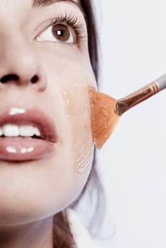 Close-up of a young woman applying a facial mask