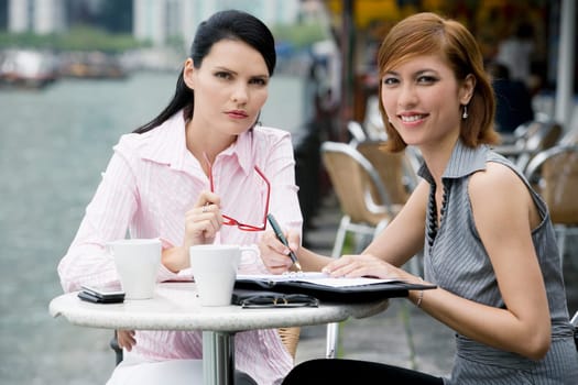Portrait of two businesswomen sitting at a sidewalk cafe