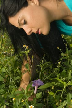 Close-up of a young woman picking up a flower
