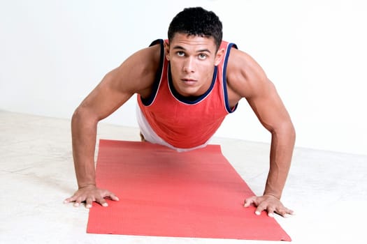 Portrait of a young man doing push-ups on an exercise mat