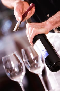 Mid section view of a man opening the cork of a wine bottle