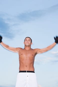 Portrait of a young man with his arms raised