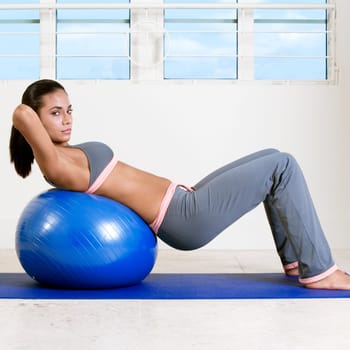 Side profile of a young woman exercising with a fitness ball