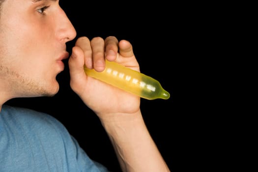 Close-up of a young man blowing a condom