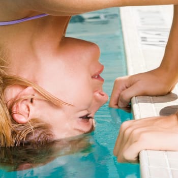 Side profile of a young woman bending forward with her hair in a swimming pool
