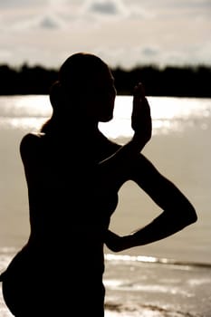Silhouette of a young woman practicing martial arts on the beach