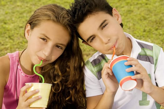 Portrait of a brother and sister drinking with straws