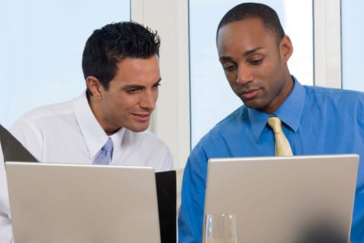 Close-up of two businessmen working in front of laptops