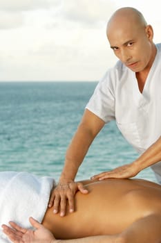 Portrait of a mature man giving a man a back massage
