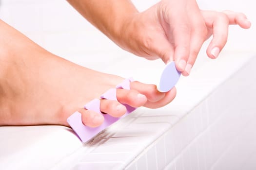 Close-up of a womanŽs hand shaping her toenail with a nail file