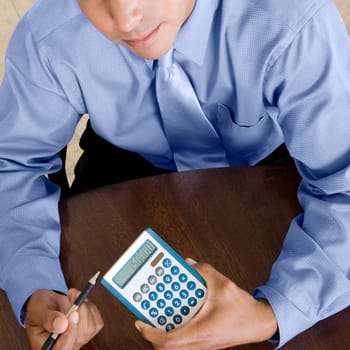 High angle view of a businessman holding a calculator and a pen