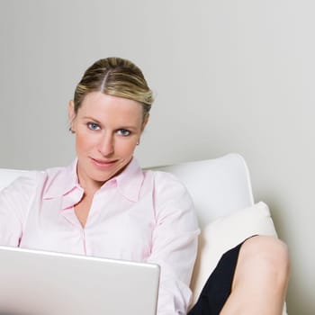Portrait of a businesswoman sitting on the bed holding a laptop