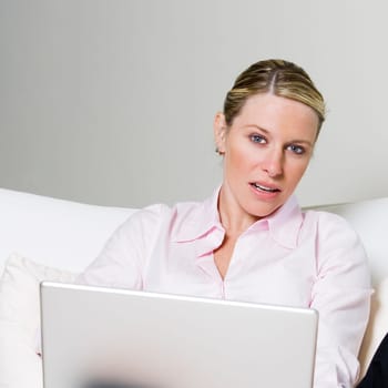 Portrait of a businesswoman sitting on the bed holding a laptop