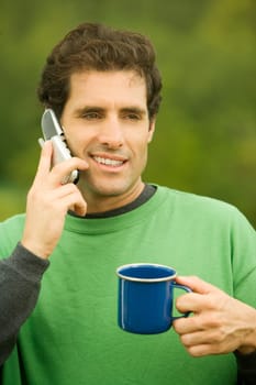 Close-up of a mid adult man talking on a mobile phone holding a coffee cup