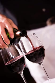 Mid section view of a man pouring red wine into a wineglass