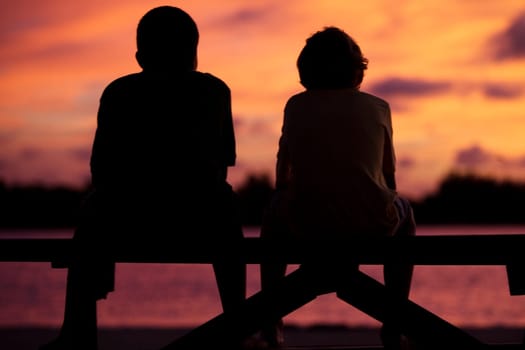 Silhouette of two boys sitting on a picnic table