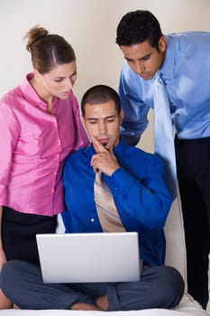Two businessmen and a businesswoman in front of a laptop