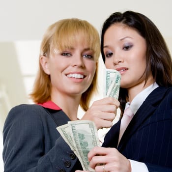 Low angle view of a businesswoman showing a dollar bill to another businesswoman