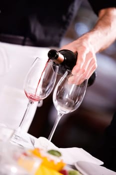 Mid section view of a man pouring red wine into a wineglass