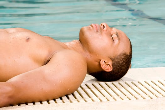 Side profile of a young man lying at the poolside