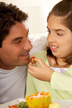 Close-up of a daughter feeding her father a strawberry