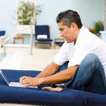 Side profile of a mid adult man using a laptop