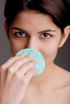 Portrait of a young woman scrubbing her nose with a sponge