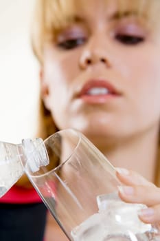 Close-up of a young woman pouring water into a glass