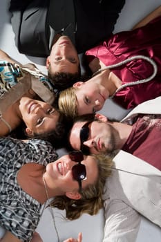 High angle view of three young women with two young men lying on the floor