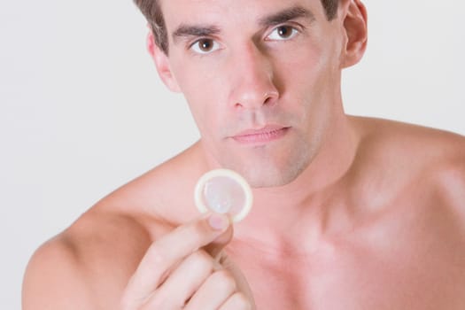 Portrait of a young man holding a condom