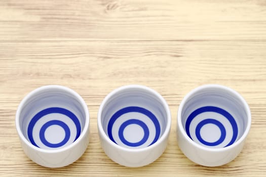 Japanese sake in traditional ceramic ochoko cup on wooden table