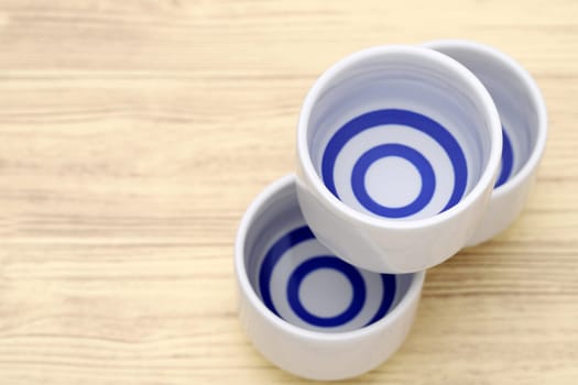 Japanese sake in traditional ceramic ochoko cup on wooden table