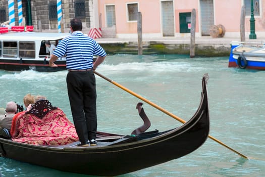 Man standing on a gondola in a canal, Grand Canal, Venice, Italy