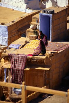 Woman drying sari on the roof of a house, Jaisalmer, Rajasthan, India