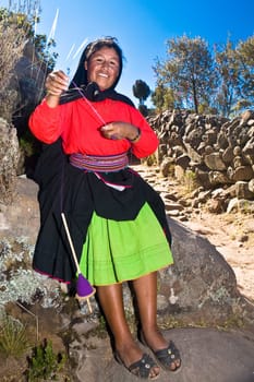 Portrait of a young woman spinning a reel of thread, Taquile Island, Lake Titicaca, Puno, Peru
