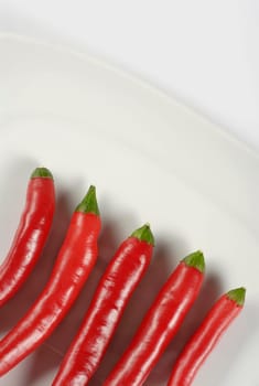 High angle view of five red chili peppers in a plate