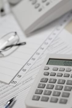 Calculator and telephone with eyeglasses on paper