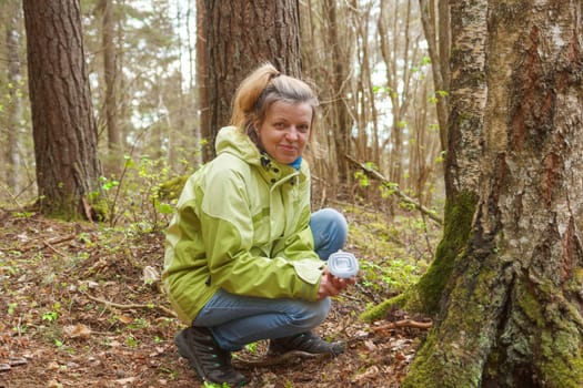 A woman geocaching. Women in woods find geocache container. Big ammo box with log book and some toys.