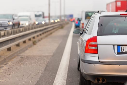 Car stucked in traffic jam on full road from back. Automobiles waiting on crowded highway with vehicles in opposite side. Collaps on motorway during rush hour.
