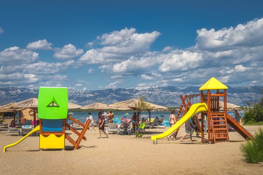 Nin, Croatia, July 2019 Kids playground on Zdrijac beach between Nin bay and Adriatic Sea with mountain range of Dinaric Alps in the background