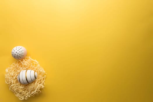 Colored Easter eggs in nest on yellow background. High quality photo