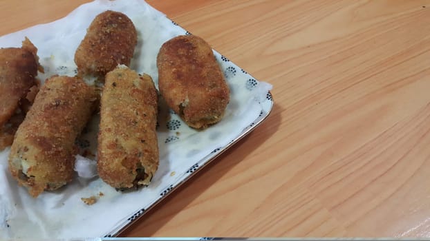 Closeup perspective view of home made spicy and delicious croquettes served in ceramic plate over wooden floor