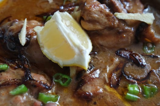 Closeup view of traditional Pakistani Haleem dish with salad and Lemon juice.