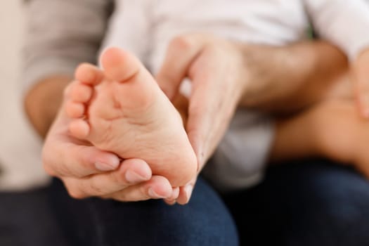 Father's hands carefully keeping baby's foot with tenderness.
