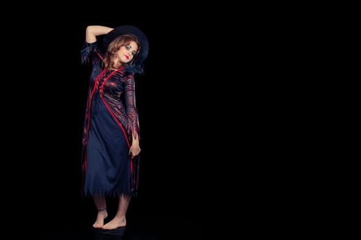 girl dressed as a witch portrayed on black background, wearing black pointing hat