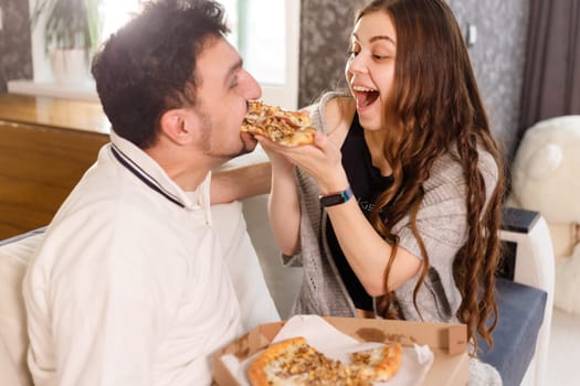 Girl feeds her husband with two slices of pizza. Exaggerate and wondering. Much credit on yourself and capabilities concept.