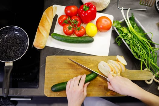 Woman cutting vegetables in kitchen. Top view.