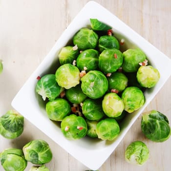 Close up Fresh Green Brussels Sprouts on White Bowl Placed on Top of Wooden Table.